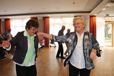 Zwei Seniorinnen tanzen und lachen