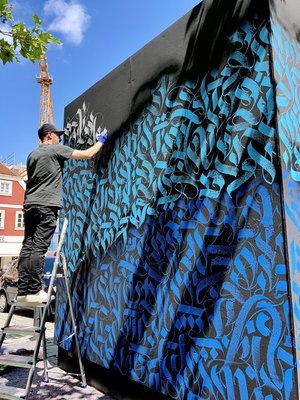 Künstler bei der Arbeit an einem Graffiti-Würfel unter freiem Himmel