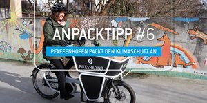 Frau fährt auf einem E-Lastenrad mit Logo der Stadtwerke